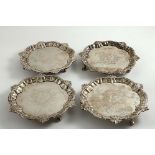 A SET OF FOUR GEORGE II WAITERS of shaped circular outline with shell and scroll borders, engraved
