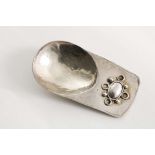 AN ARTS & CRAFTS HANDMADE CADDY SPOON with a hammered finish, an egg-shaped bowl and a lug handle