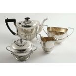 AN EDWARDIAN THREE-PIECE TEA SET of part-fluted oval form with angular handles, initialled, by