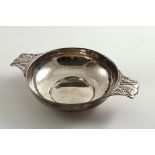 A LATE VICTORIAN SHALLOW CIRCULAR DISH with a hammered finish and twin, pierced handles, the