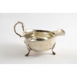 A GEORGE II SAUCE BOAT on three legs with a leaf-capped scroll handle, crested, by John Pollock,
