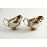 A PAIR OF EARLY 20TH CENTURY SAUCE BOATS with a hammered finish, loop handles and spreading oval