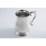 A GEORGE III BALUSTER MUG with a spreading foot and a leaf-capped scroll handle, initialled, by