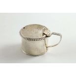 A GEORGE III DRUM MUSTARD POT with a gadrooned border and a reeded, angular handle, the cover