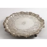 A GEORGE II SALVER of shaped circular outline with a husk and foliate scroll border, and paw feet,