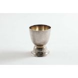 AN EARLY 20TH CENTURY EGG CUP with a hammered finish & a domed foot with an incised, repeating