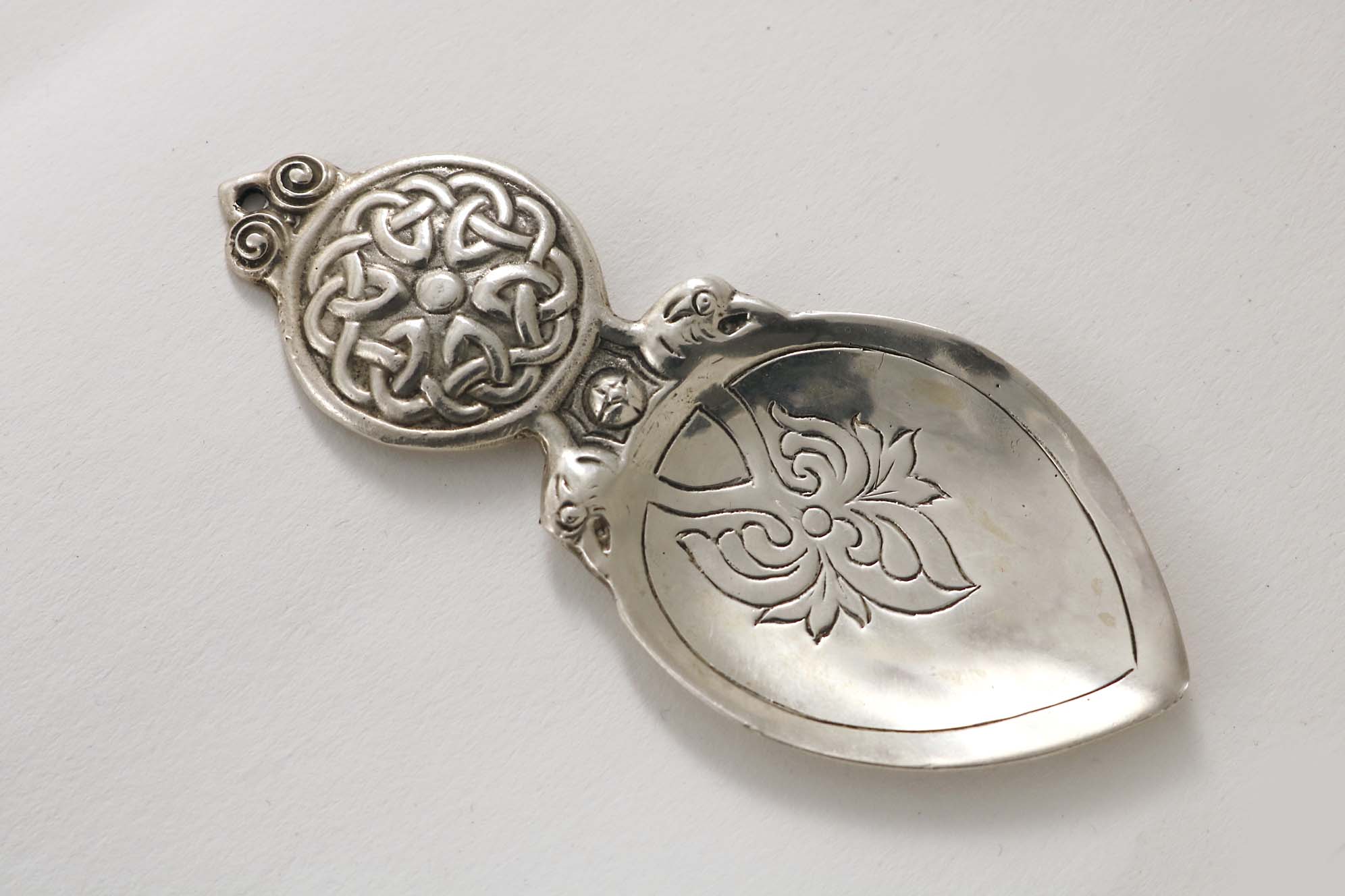 A SCOTTISH CAST CADDY SPOON with a circular lug handle, decorated with "Celtic" knots, and a spade-