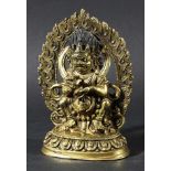 TIBETAN BRASS FORTUNE BUDDHA, modelled seated before a flaming arch on a lotus base, height 16.5cm