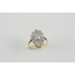 A DIAMOND CLUSTER RING of flowerhead form, the central cushion-shaped diamond is set within a