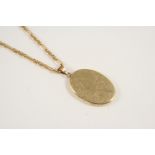 A 9CT. GOLD LOCKET PENDANT of oval-shape, with carved foliate decoration to front case, 4cm. long,