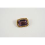 AN AMETHSYT AND GOLD BROOCH the rounded rectangular-shaped amethyst is set within a 15ct. gold