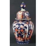 JAPANESE IMARI VASE AND COVER, 19th century, of reeded ovoid form, with panels of vases or flowers
