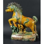 CHINESE SANCAI RIDGE TILE, modelled as a leaping horse supported by a scrolling wave, height 38cm