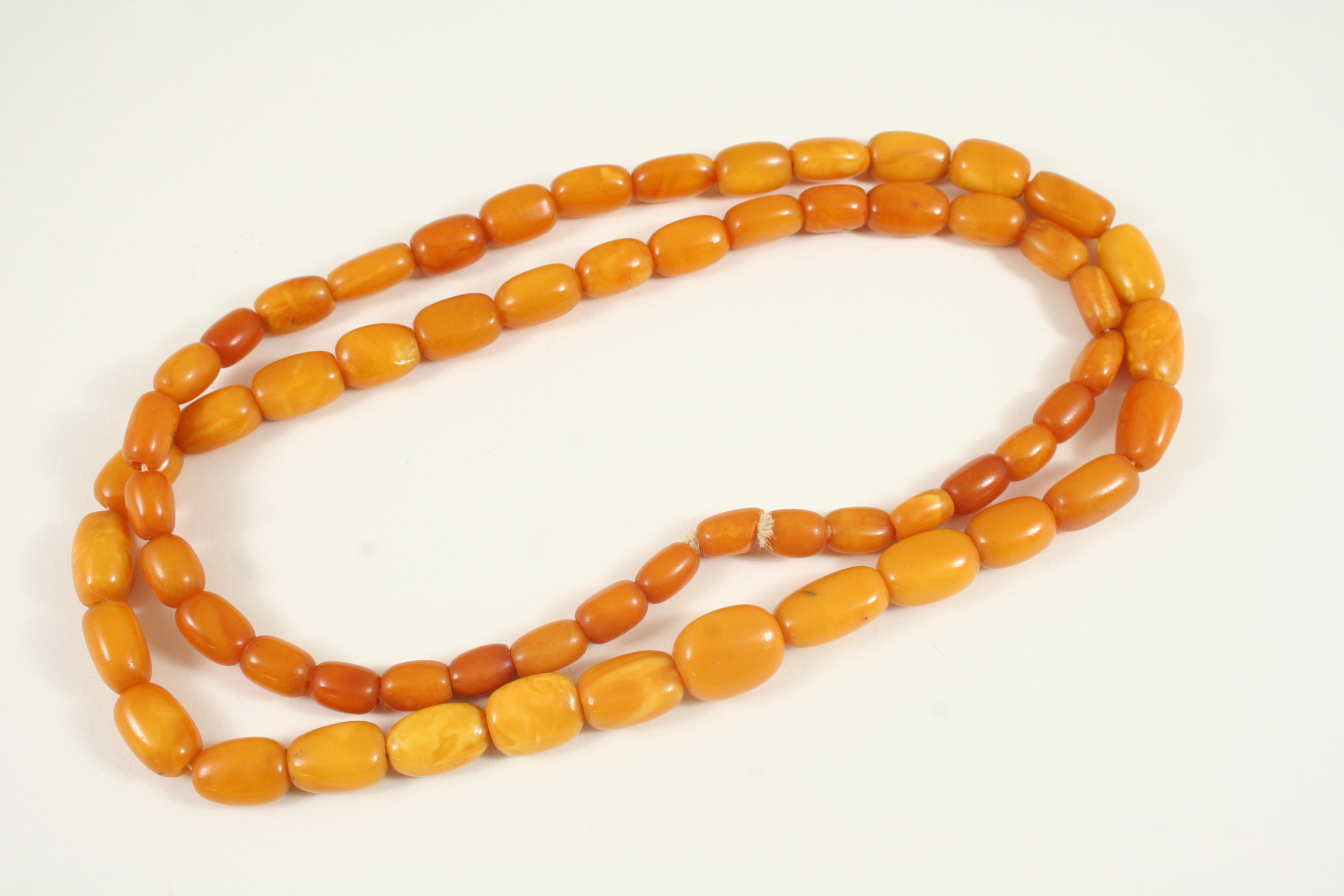 A SINGLE ROW GRADUATED AMBER BEAD NECKLACE 92cm. long, 64 grams.