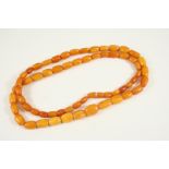 A SINGLE ROW GRADUATED AMBER BEAD NECKLACE 92cm. long, 64 grams.
