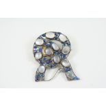 AN ARTS AND CRAFTS MOONSTONE, SAPPHIRE AND ENAMEL BROOCH ATTRIBUTED TO GEORGE EDWARD HUNT (1892-