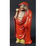 CHINESE FIGURE OF A MONK, late 19th or 20th century, standing wearing a red cloak and holding a gilt