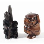 TWO JAPANESE WOODEN NETSUKE, one carved as two men, one carrying a large parasol, the other as a