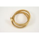 A GOLD SNAKE BRACELET the coiled woven link snake realistically formed, the head with cabochon