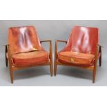 A PAIR OF LEATHER DESIGNER ARMCHAIRS with wide wooden arms and tapering legs.