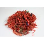 A RED LEATHER JEWELLERY BOX containing various pieces of coral necklaces and loose coral beads.
