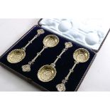 A VICTORIAN CASED SET OF FOUR SILVERGILT FRUIT SPOONS with cast stems & embossed decoration in the