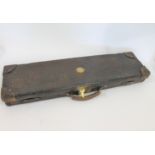 LEATHER GUN CASE the lid inset with a brass roundel, the interior with various compartments and with