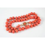 A SINGLE ROW GRADUATED CORAL NECKLACE the graduated coral roundells are set to a gold oval shaped