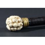JAPANESE WALKING STICK, the ivory finial carved with numerous masks on an ebony shaft, length 85cm