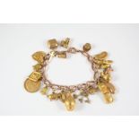 A 9CT. GOLD CHARM BRACELET suspending assorted charms, including a gold half sovereign, 1905, in a