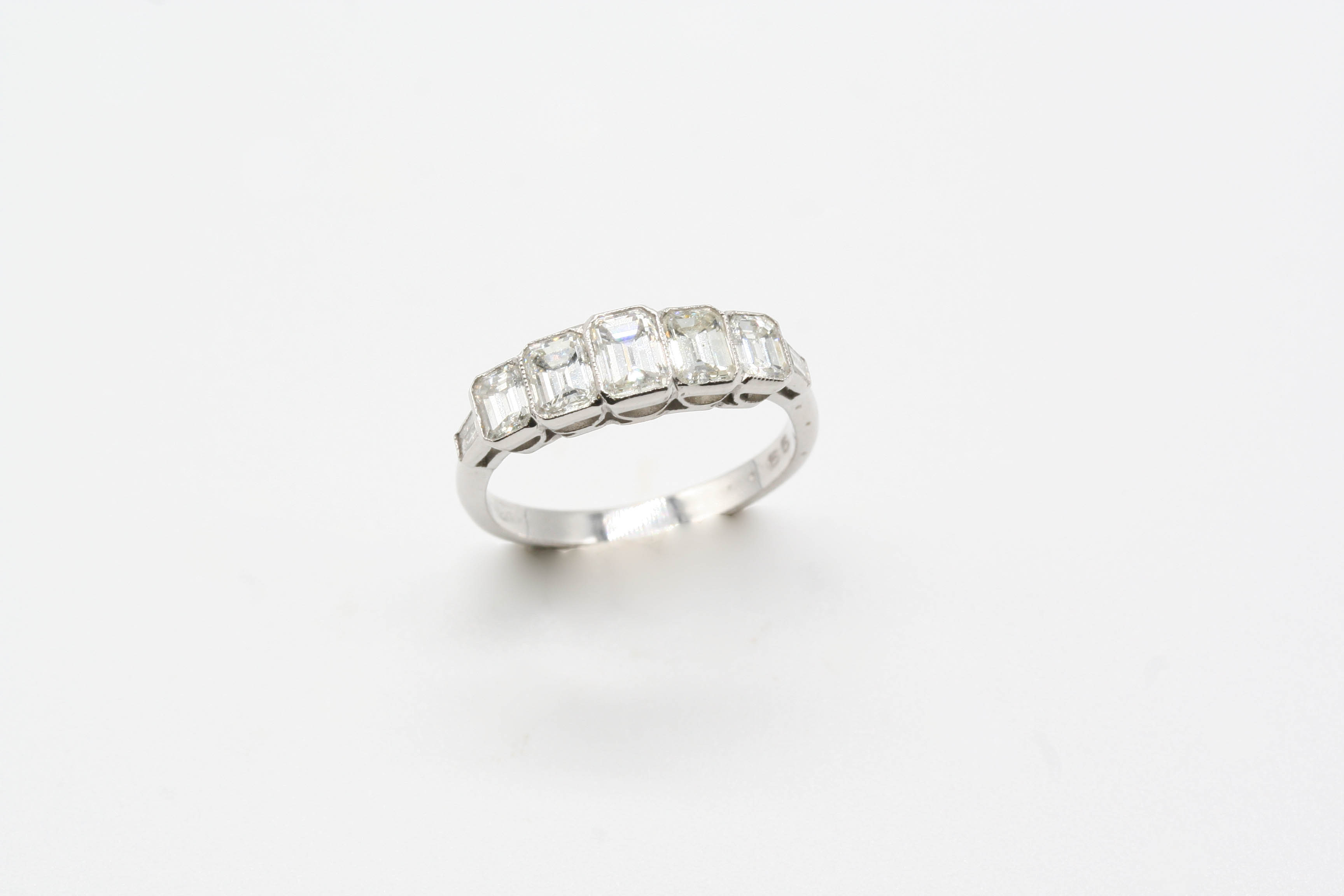 A DIAMOND FIVE STONE RING the five graduated emerald-cut diamonds are set in 18ct. white gold.