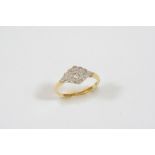 A DIAMOND CLUSTER RING of marquise-shape, the circular-cut diamond is set within a surround of