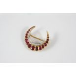 A RUBY AND DIAMOND CLOSED CRESCENT BROOCH mounted with graduated oval-shaped rubies and circular-cut