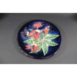 LARGE MOORCROFT WALL PLATE in the Simeon design, the flowers painted on a blue ground. Designed by