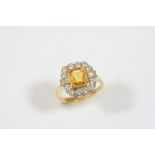 A YELLOW SAPPHIRE AND DIAMOND CLUSTER RING the cut cornered rectangular-shaped sapphire is set