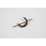 A SAPPHIRE CLOSED CRESCENT BROOCH formed with graduated oval-shaped sapphires, in gold, 5.4cm.