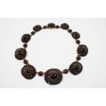 A VICTORIAN GARNET NECKLACE formed with graduated garnet clusters, each centred with an oval