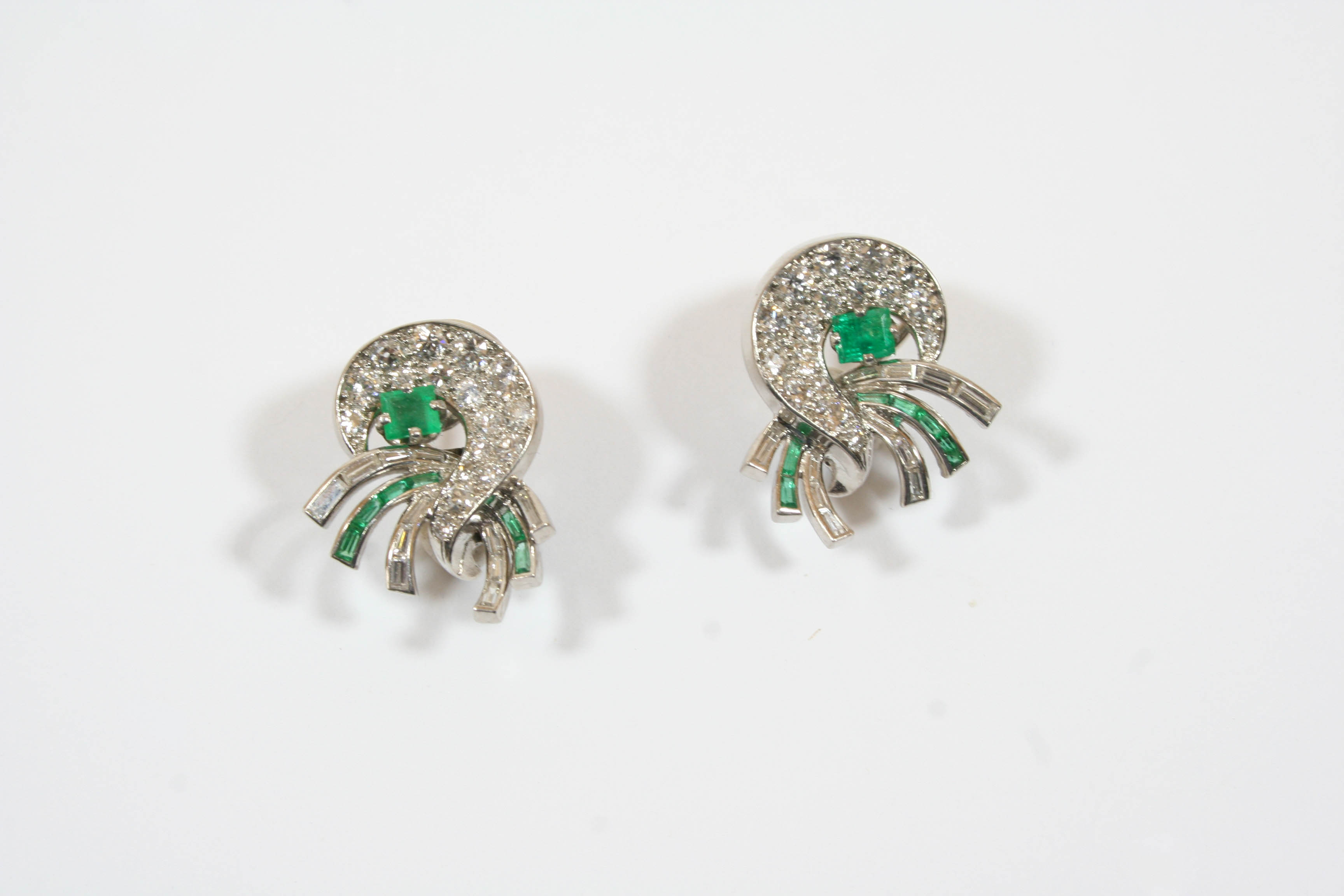 A PAIR OF DIAMOND AND EMERALD EARCLIPS BY J.E. CALDWELL of scrolling design, each mounted with a
