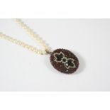 AN EARLY 20TH CENTURY GARNET AND PEARL LOCKET PENDANT the gold double sided locket is set with