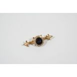 A SAPPHIRE AND DIAMOND CLUSTER BROOCH the oval-shaped sapphire is set within a surround of