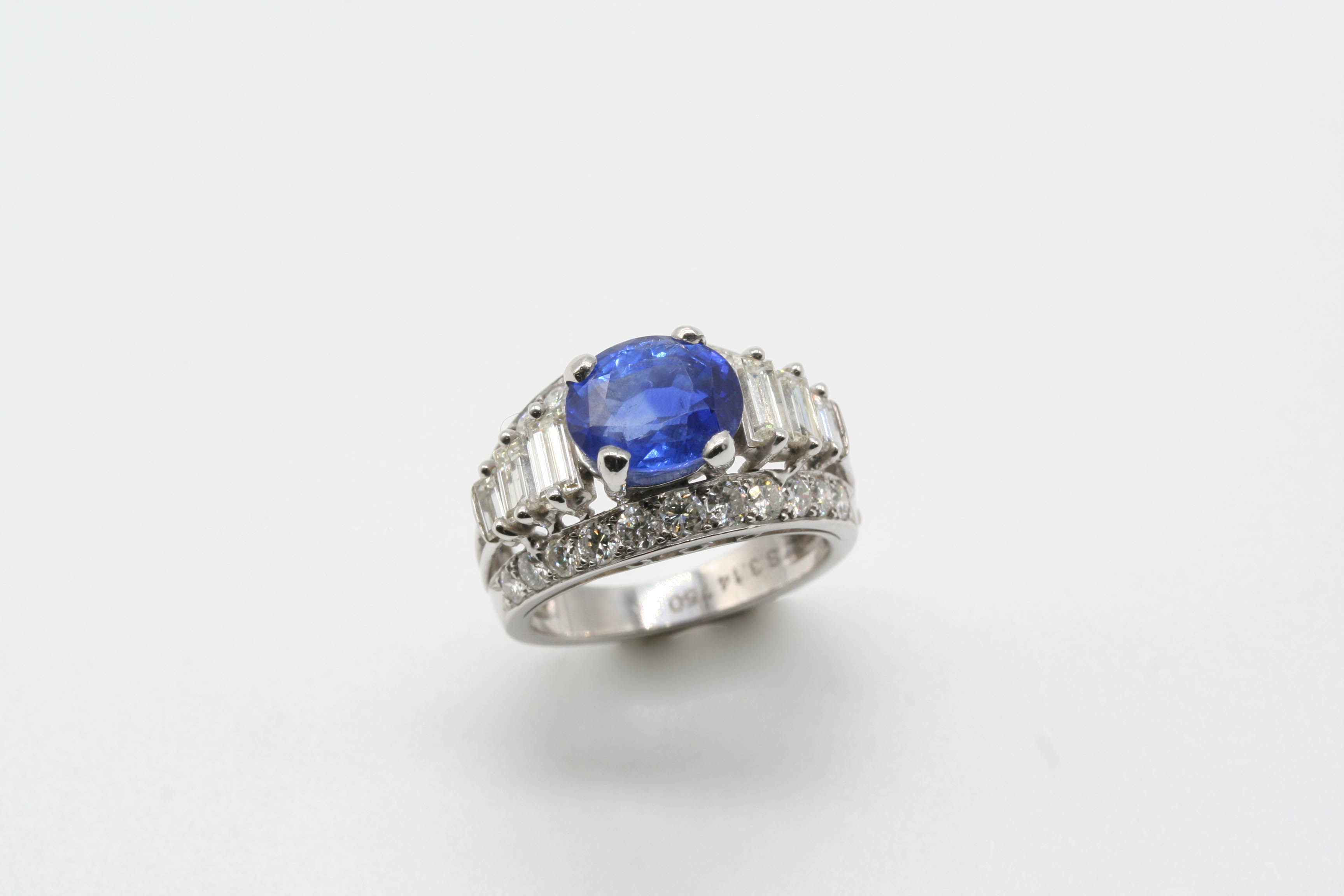 A SAPPHIRE AND DIAMOND RING the oval-shaped sapphire weighs 3.14 carats and is set within a surround