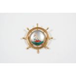 A REVERSE CARVED CRYSTAL INTAGLIO BROOCH depicting a ship's wheel, the intaglio depicting a yacht in