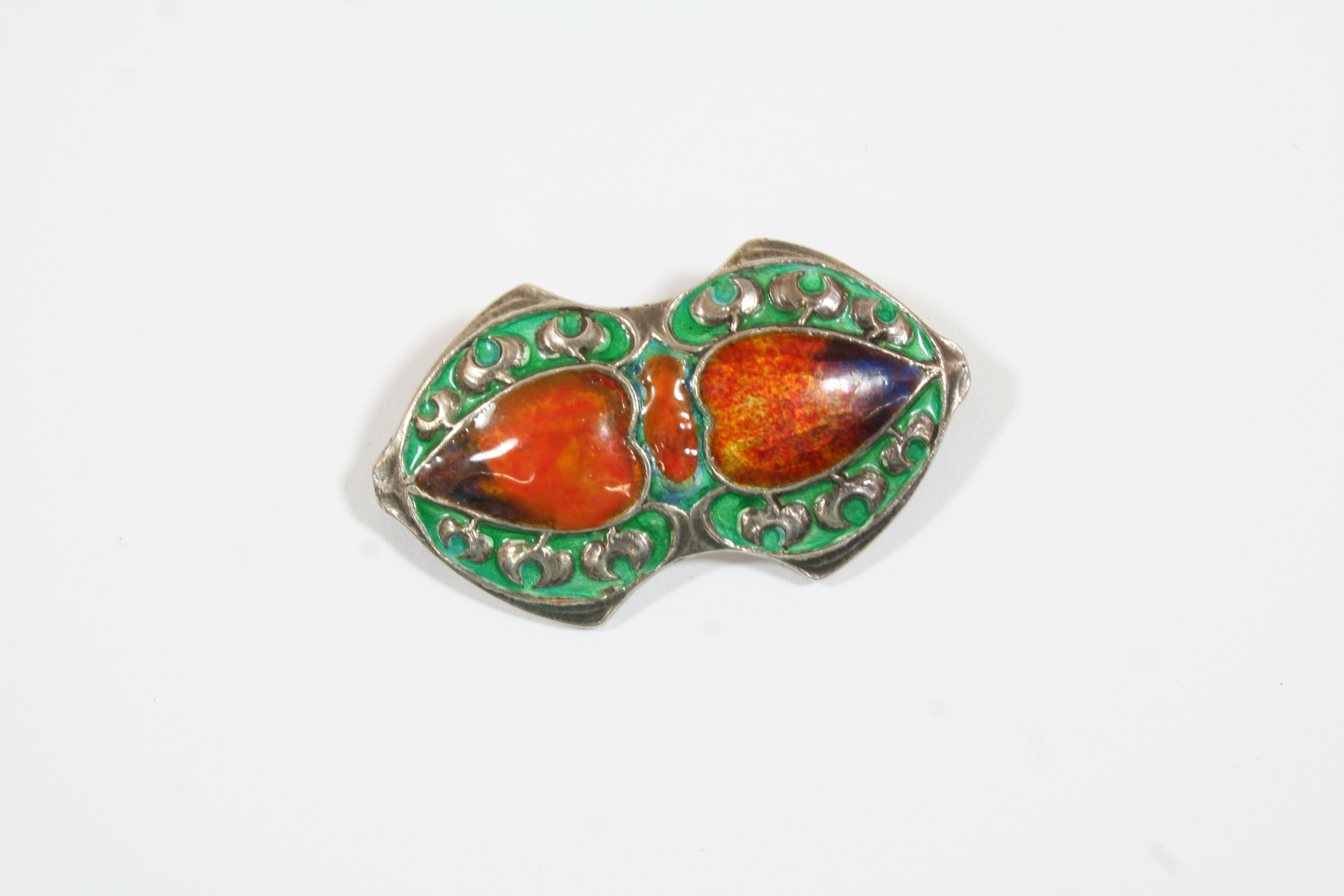 AN ENAMEL AND SILVER BROOCH BY MURRLE BENNETT & CO. centred with two heart motifs decorated with