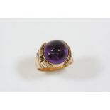 AN AMETHYST SINGLE STONE RING the circular cabochon amethyst is set in gold, with ornate geometric