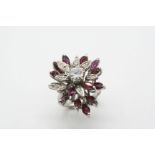 A RUBY AND DIAMOND CLUSTER RING the flowerhead design is centred with a circular-cut diamond, with