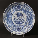 CHINESE BLUE AND WHITE SAUCER DISH, Kangxi marks but later, a central flower above waves, the border