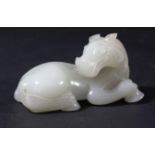 CHINESE WHITE OR PALE CELADON JADE HORSE, recumbent, looking over its back, length 8cm