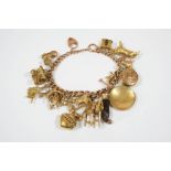 A 9CT. GOLD CURB LINK CHARM BRACELET with padlock clasp and suspending many assorted gold charms,