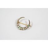 A VICTORIAN DIAMOND AND OPAL CLOSED CRESCENT BROOCH formed with graduated circular solid white opals