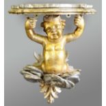 GILTWOOD CHERUB WALL BRACKET, with silvered clouds and a serpentine, marble topped shelf, height